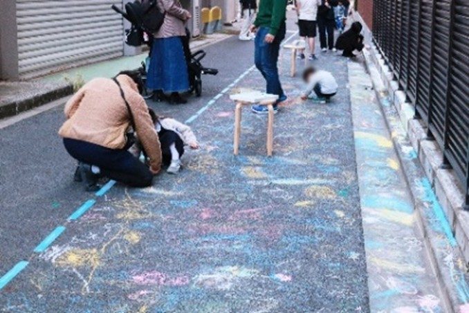 道路にチョークで絵を描く親子（千代田区のウォーカブルな活動の様子）